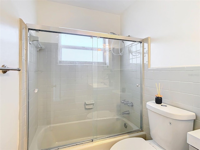 full bathroom with vanity, bath / shower combo with glass door, tile walls, and toilet