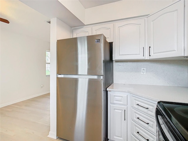 kitchen with white cabinetry, backsplash, stainless steel refrigerator, and light hardwood / wood-style flooring