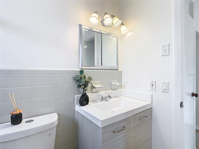 bathroom featuring vanity, toilet, and tile walls