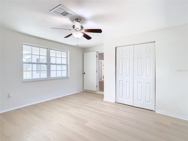 unfurnished bedroom with ceiling fan, light wood-type flooring, and a closet