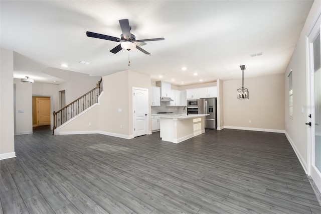 unfurnished living room featuring dark wood-type flooring, sink, and ceiling fan