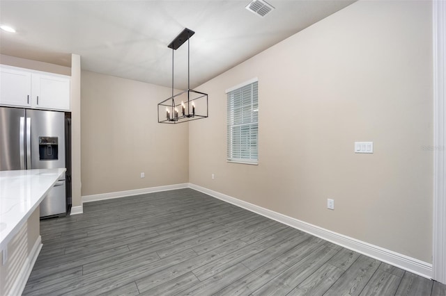 kitchen with white cabinetry, hanging light fixtures, hardwood / wood-style floors, and light stone countertops