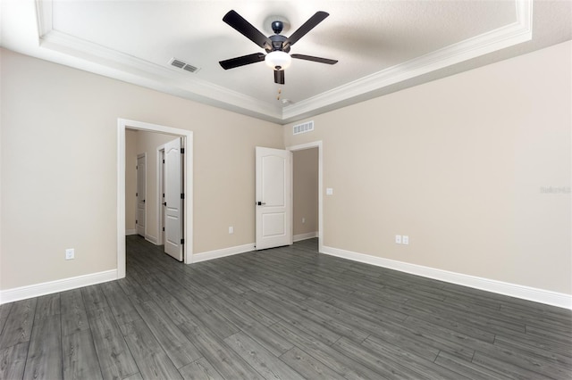 unfurnished bedroom featuring ornamental molding, ceiling fan, dark hardwood / wood-style floors, a textured ceiling, and a tray ceiling