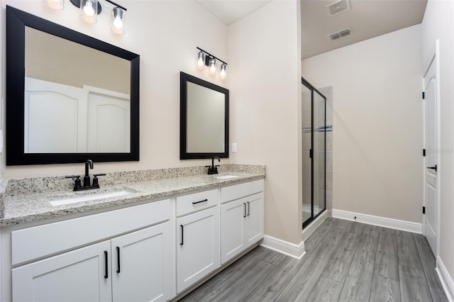 bathroom with wood-type flooring, vanity, and a shower with shower door