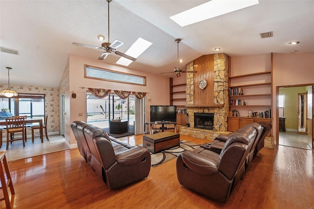 living room featuring a stone fireplace, a wealth of natural light, ceiling fan, and wood-type flooring