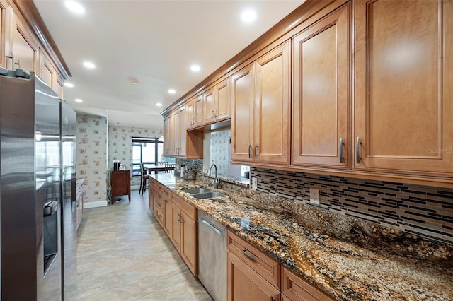 kitchen with backsplash, stainless steel appliances, dark stone counters, and sink