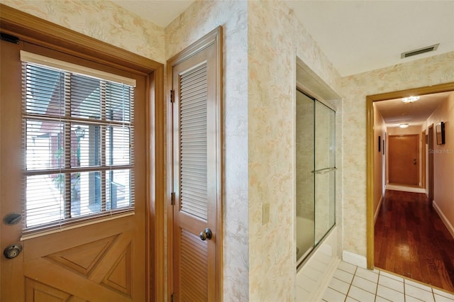 interior space featuring hardwood / wood-style floors, a healthy amount of sunlight, and shower / bath combination with glass door