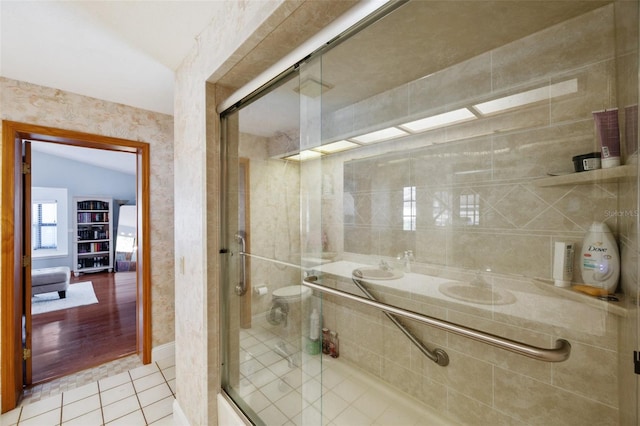 bathroom with lofted ceiling, a shower with door, tile patterned floors, toilet, and double sink