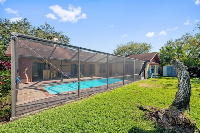 view of pool featuring glass enclosure, a shed, a yard, and a patio