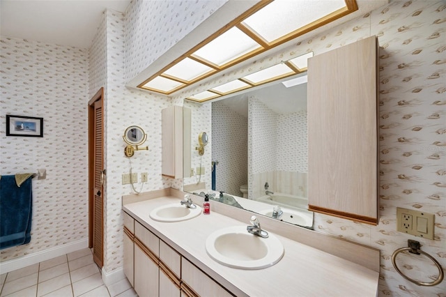 bathroom featuring vanity, a skylight, tile patterned flooring, a washtub, and toilet