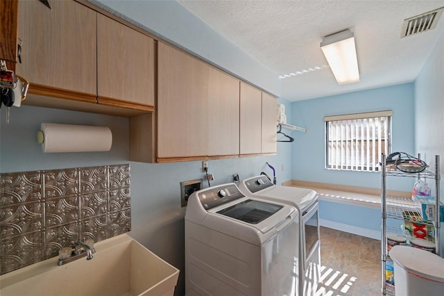 laundry area with cabinets, independent washer and dryer, a textured ceiling, and sink