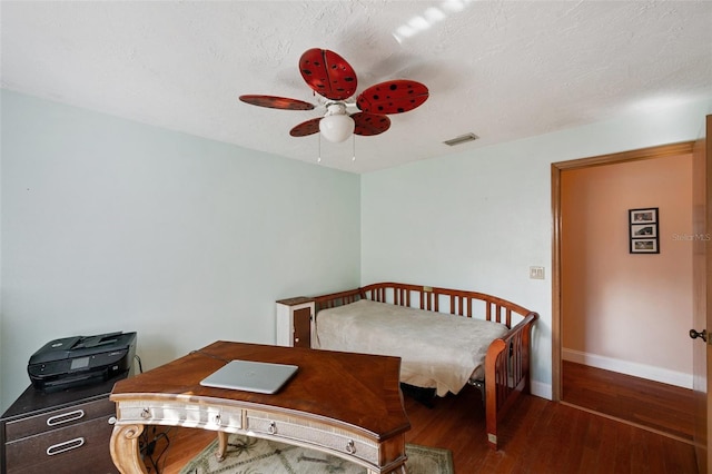 bedroom with ceiling fan, dark hardwood / wood-style floors, and a textured ceiling