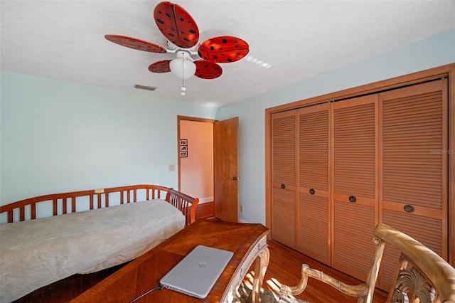 bedroom featuring a textured ceiling, a closet, hardwood / wood-style flooring, and ceiling fan