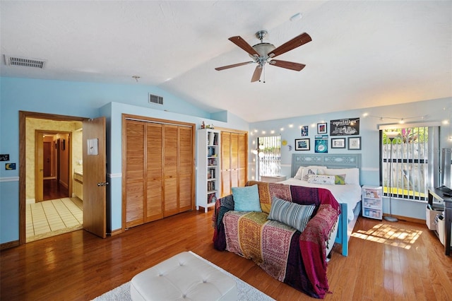 bedroom with hardwood / wood-style flooring, ceiling fan, multiple windows, and multiple closets