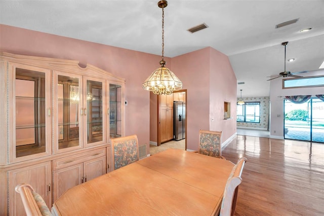 dining area with ceiling fan with notable chandelier and light hardwood / wood-style flooring