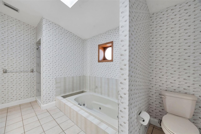 bathroom with a relaxing tiled tub, tile patterned flooring, lofted ceiling, and toilet