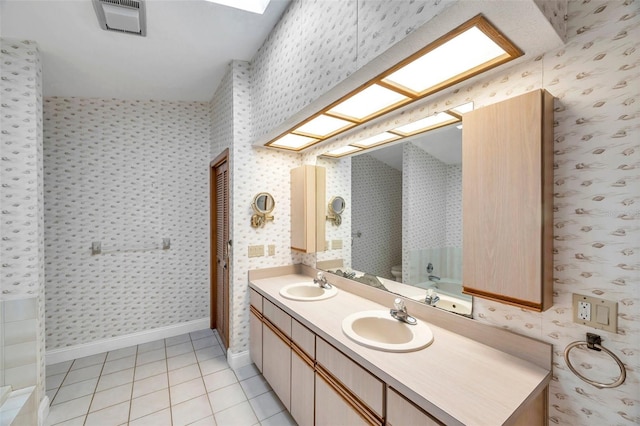 bathroom with vanity, toilet, a skylight, and tile patterned flooring