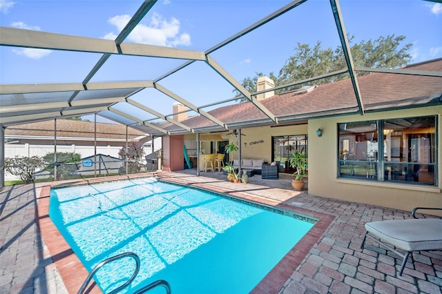 view of pool featuring a patio, outdoor lounge area, and glass enclosure