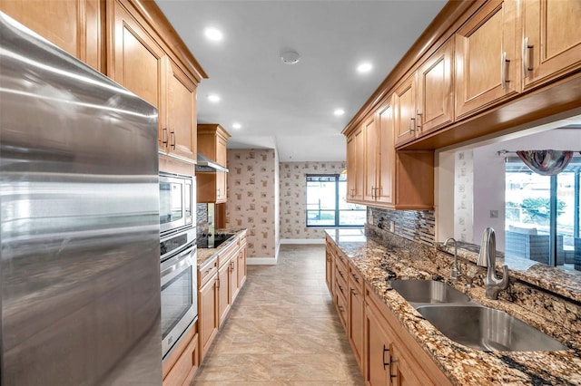 kitchen with sink, decorative backsplash, dark stone counters, and appliances with stainless steel finishes