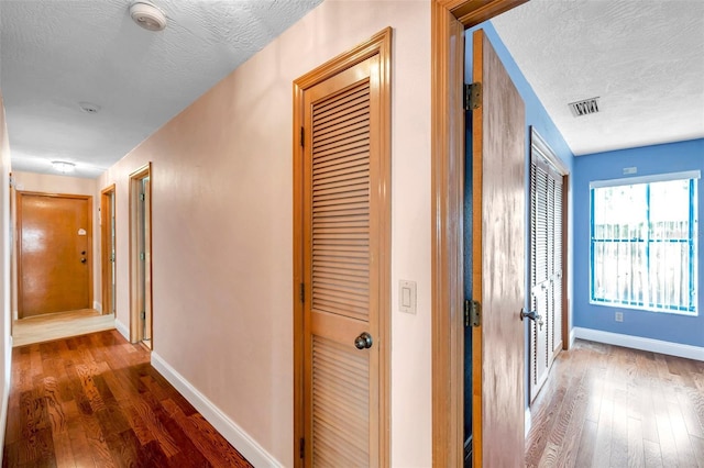 corridor with dark hardwood / wood-style floors and a textured ceiling