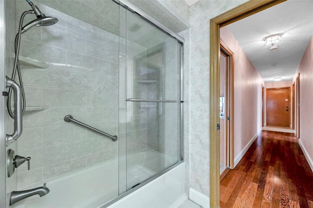 bathroom with wood-type flooring and combined bath / shower with glass door