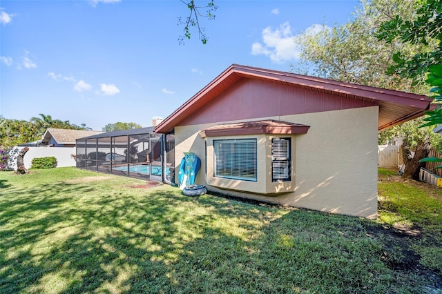 rear view of property featuring a fenced in pool, a lanai, and a lawn