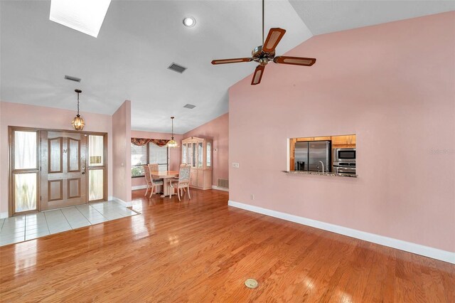 unfurnished living room featuring ceiling fan, high vaulted ceiling, and light hardwood / wood-style flooring