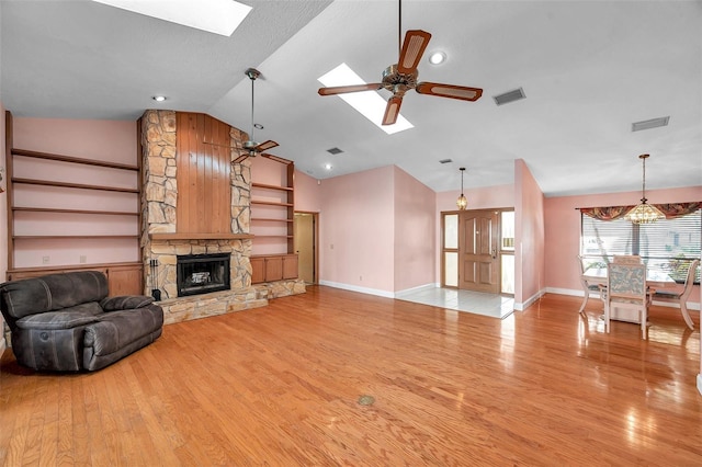 unfurnished living room with a skylight, built in features, and ceiling fan