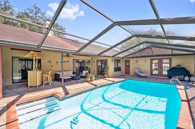 view of pool with french doors, a patio area, glass enclosure, outdoor lounge area, and a bar