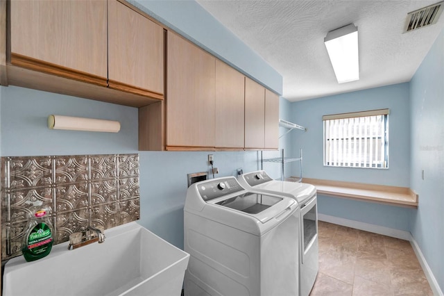 laundry area with cabinets, separate washer and dryer, sink, and a textured ceiling