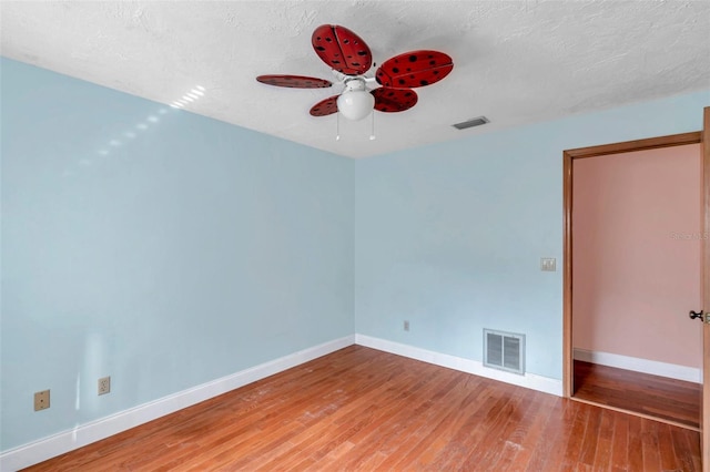 empty room featuring ceiling fan, hardwood / wood-style floors, and a textured ceiling