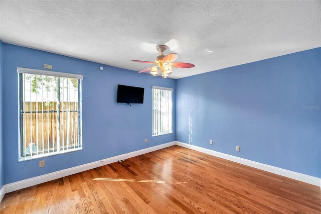 unfurnished room featuring plenty of natural light, hardwood / wood-style floors, a textured ceiling, and ceiling fan