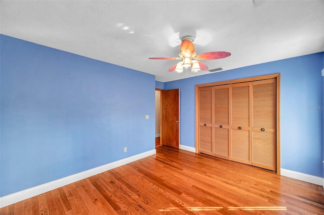 unfurnished bedroom featuring ceiling fan, a closet, and light wood-type flooring