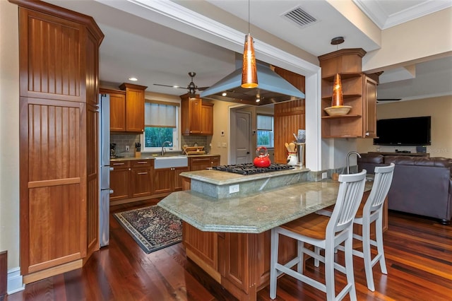 kitchen with island range hood, stainless steel appliances, dark hardwood / wood-style floors, sink, and kitchen peninsula