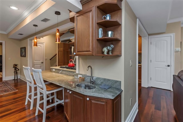 kitchen with crown molding, dark hardwood / wood-style floors, light stone countertops, sink, and a breakfast bar