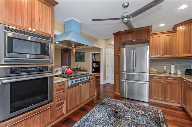 kitchen featuring stainless steel appliances, light stone counters, backsplash, island exhaust hood, and dark hardwood / wood-style flooring