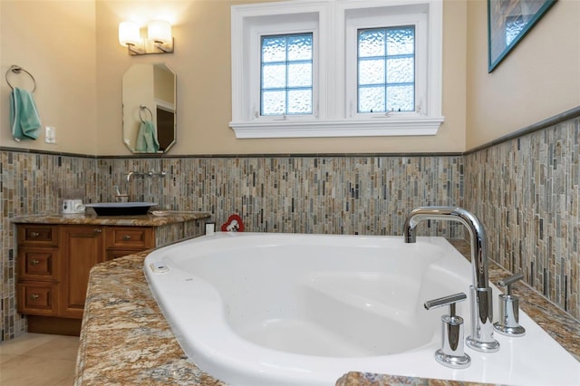 bathroom with tile patterned flooring, vanity, a bathing tub, and tile walls