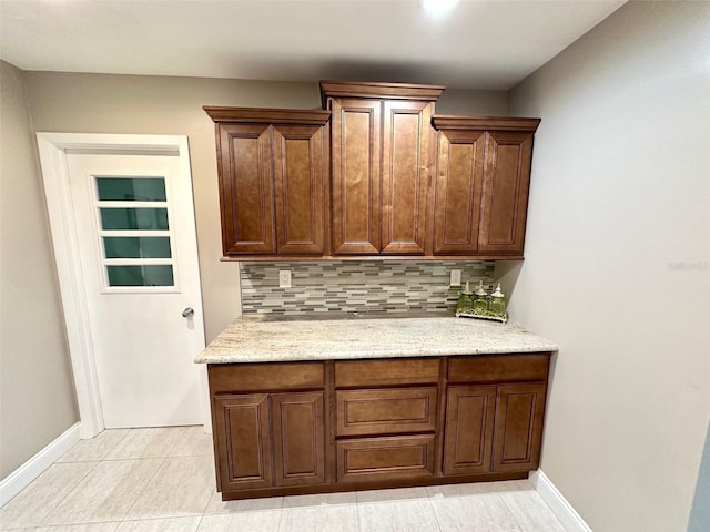 interior space featuring light tile patterned flooring, light stone counters, and decorative backsplash