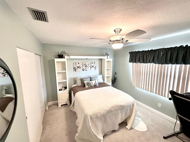 bedroom featuring ceiling fan, a textured ceiling, and light colored carpet