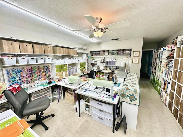 carpeted home office with a textured ceiling and ceiling fan