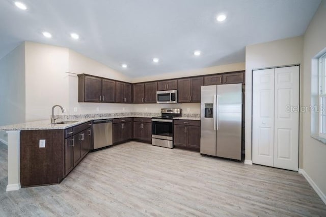 kitchen with kitchen peninsula, stainless steel appliances, sink, and light hardwood / wood-style flooring