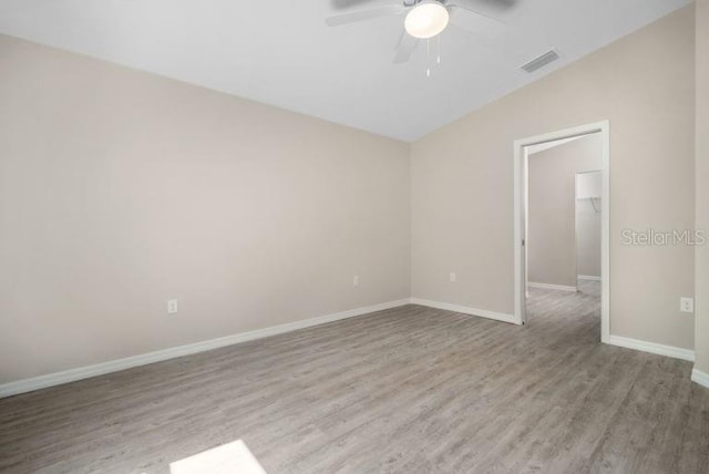 spare room featuring light wood-type flooring, vaulted ceiling, and ceiling fan