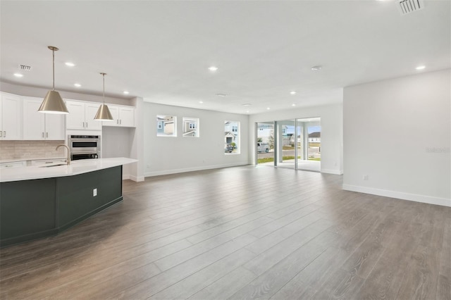 unfurnished living room featuring hardwood / wood-style flooring and sink