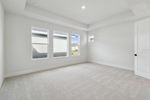 carpeted empty room featuring a raised ceiling