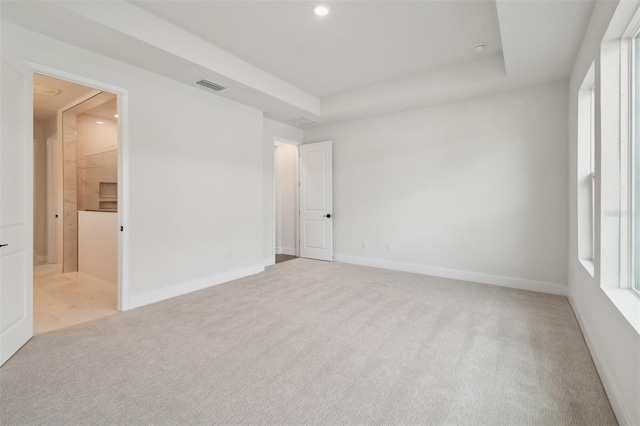 carpeted spare room with a raised ceiling