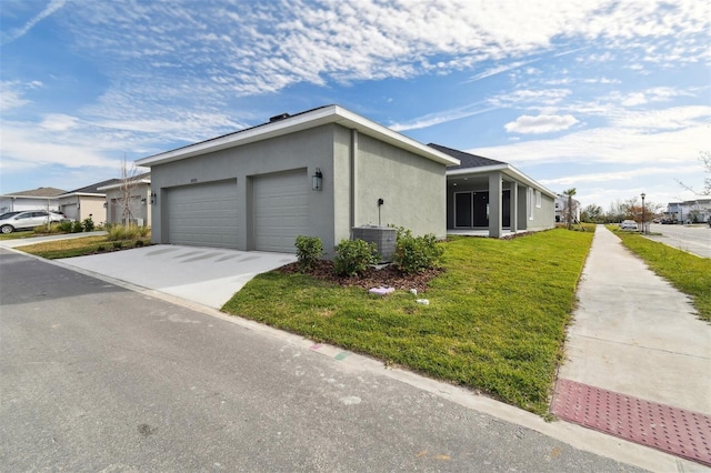 view of front of property featuring a garage, central AC unit, and a front lawn