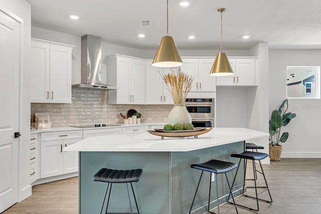 kitchen with wall chimney exhaust hood, light wood-style flooring, decorative backsplash, and recessed lighting