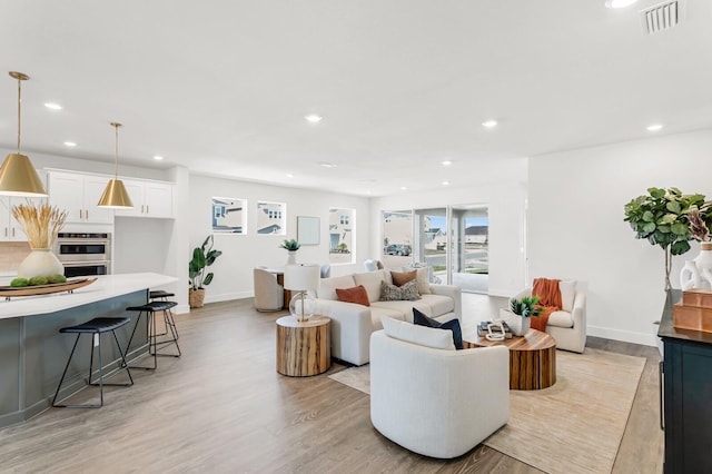 living area featuring baseboards, recessed lighting, and light wood-style flooring