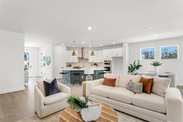 living area with baseboards, light wood-style flooring, and recessed lighting