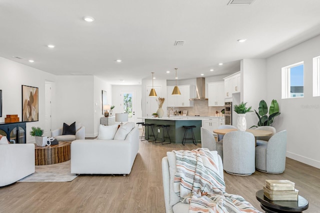 living area featuring light wood-type flooring, baseboards, and recessed lighting